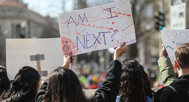 student holding Am I Next sign